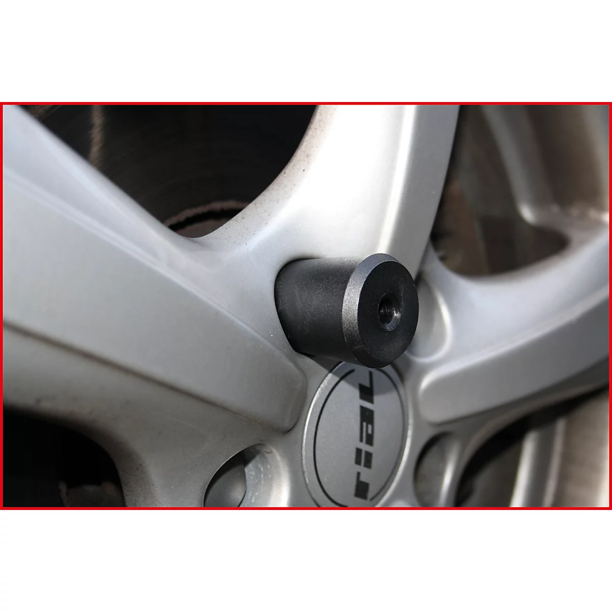 Nahaufnahme einer grauen Felge mit schwarzem Radmutternschutz, im Zentrum das Logo "rial".